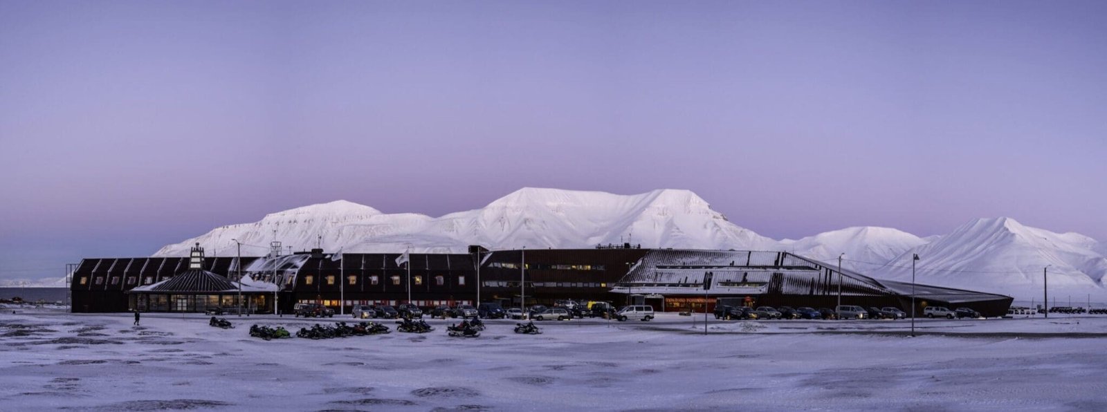 The UNIS building at dusk, with snowy mountains behind