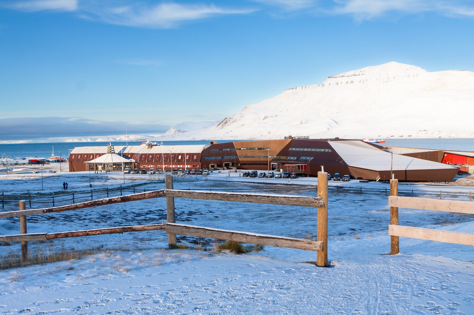 The UNIS building in snow, seen past a wooden fence
